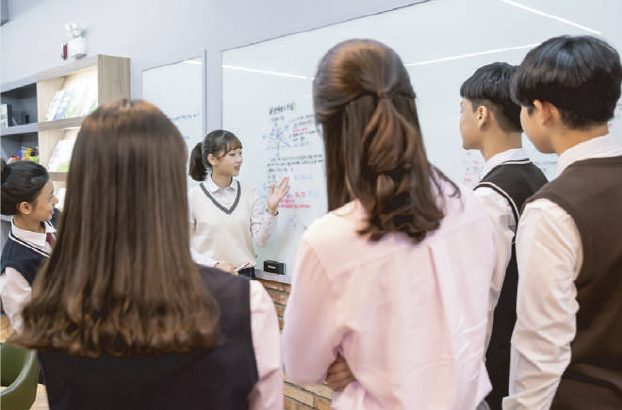 화이트보드 앞에서 학생들이 풀이를 두고 토론하는 모습